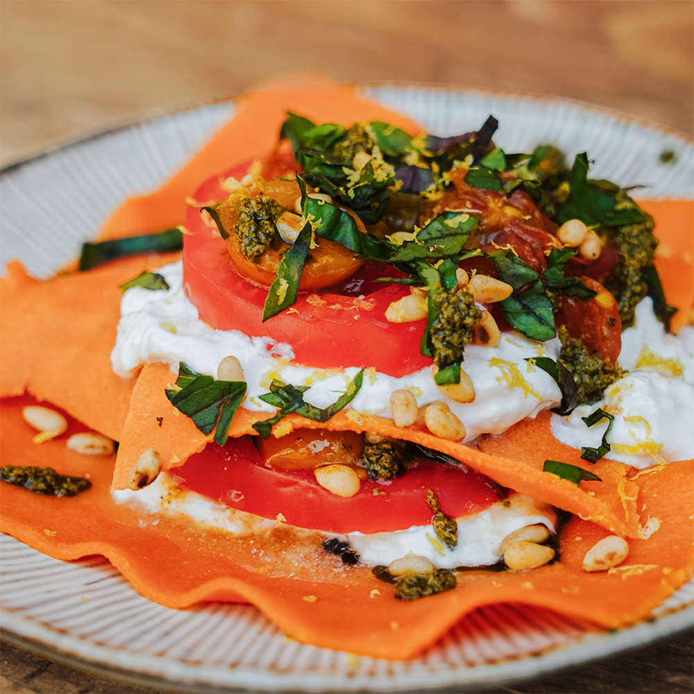Rezept Sommerlasagne mit Tomaten-Teigplatten Orangene Tomaten-Teigplatten geschichtet mit Burrata, Tomaten, Pesto. Getoppt mit gerösteten Pinienkernen, kleingehacktes Basilikum und Zitronenabrieb
