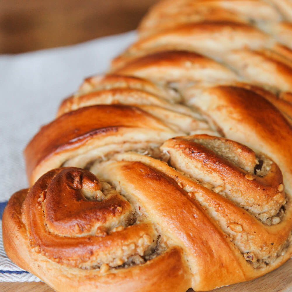 Rezept für Gefüllter Nusszopf Hefezopf gefüllt mit einer Nussfüllung auf einem grauen Tuch serviert