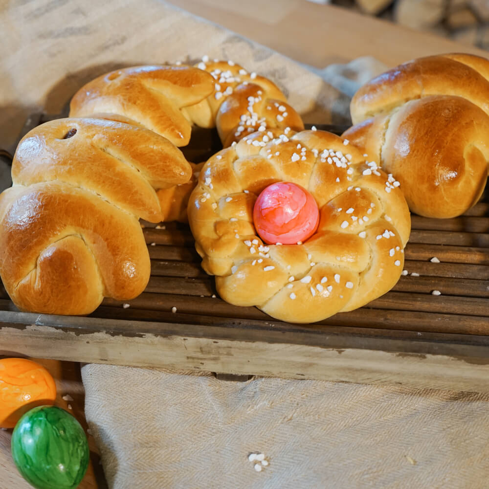 Rezept für Oster-Brioche Osterbrioche in Hasen- und Kranzform dekoriert mit Hagelzucker auf einem Holzbrett