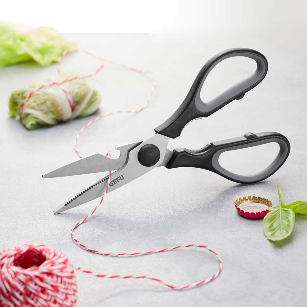 Die Schere schneidet ein rot-weißes Garn auf einer Küchenarbeitsplatte durch.