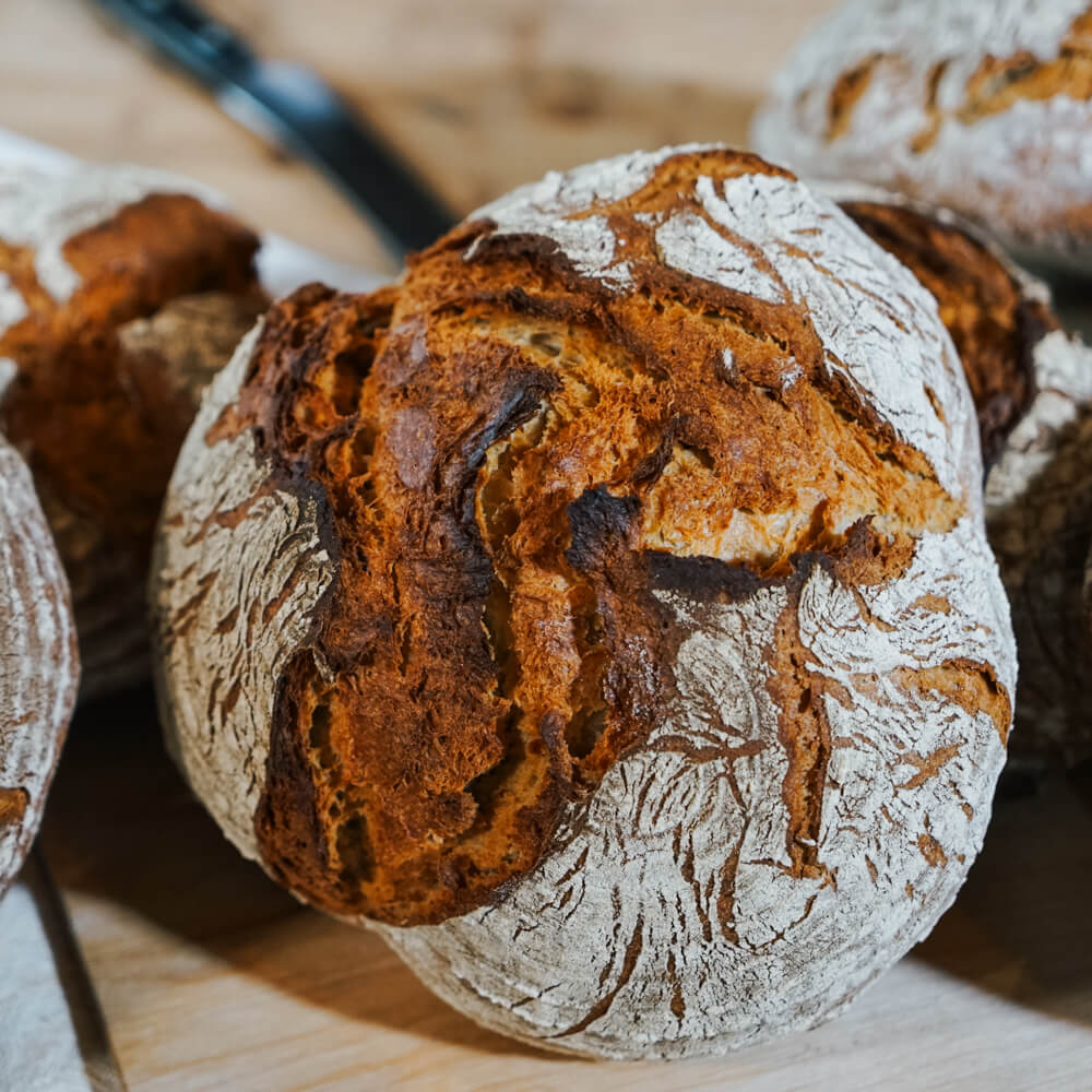 Rezept für Schwabenlaib knuspriger Schwabenlaib auf gestellt mit Holz im Hintergrund