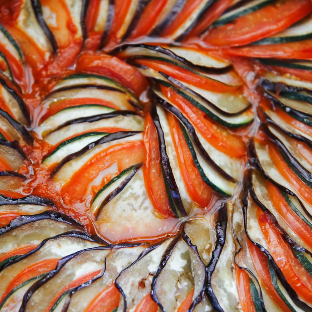 Rezept für Ratatouille buntes Ratatouille Gemüse mit Tomaten, Aubergine und Zucchini im Kreis geschichtet