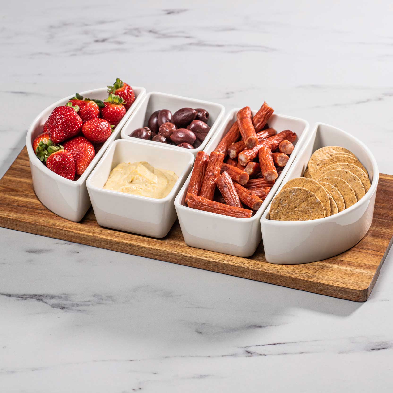 Servierplatte klein Servierplatte klein, gefüllt mit verschiedenen Snacks, platziert auf dem Akazienholz, auf einer Küchenarbeitsplatte.