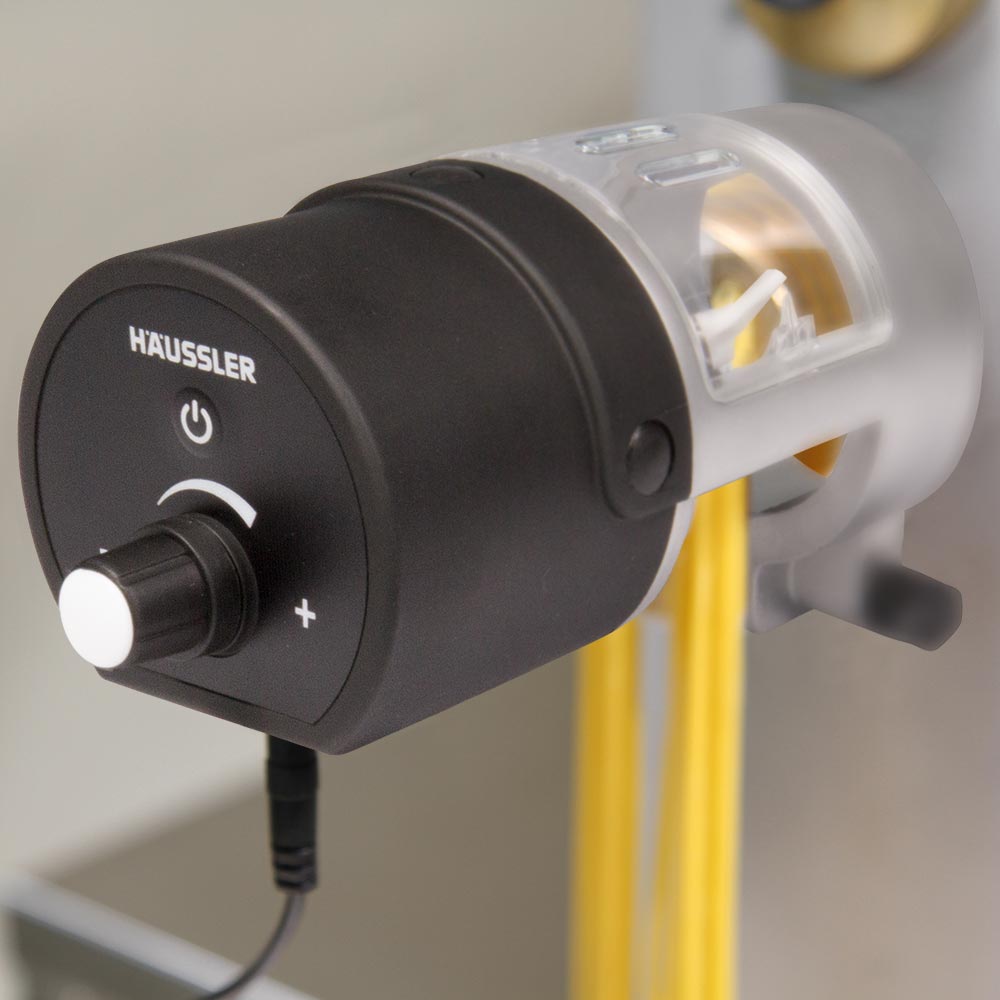 Ein länglicher Nudelschneider aus Edelstahl und schwarzem Kunststoff auf dem Spaghetti rauskommen. Auf dem schwarzen Kunststoff steht Häussler und es ist ein Drehknopf angebracht um einzustellen in welchen Abständen die Nudeln herauskommen.