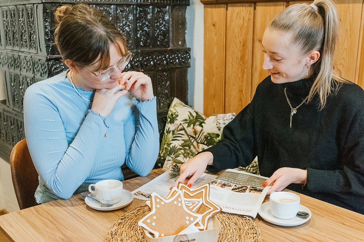 Schöne Atmosphäre beim Häussler Adventskaffee. Besucherinnen beim Adventskaffee - sie sitzen gemütlich beisammen mit Kaffeetassen und Gebäck auf dem Tisch.