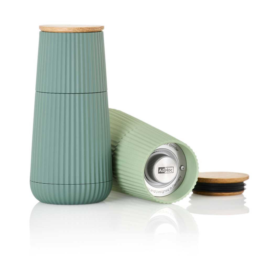 Eine Mühle in dunkelgrün steht neben einer anderen Mühle, die liegt mit geöffnetem Deckel