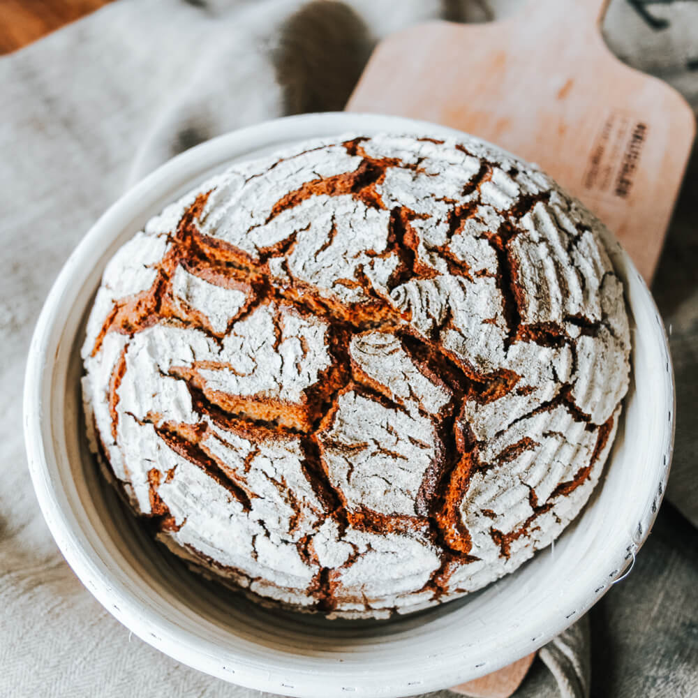 leckeres Roggenvollkornbrot in einer Peddigrohr Form gebacken und auf einem Backschieber serviert