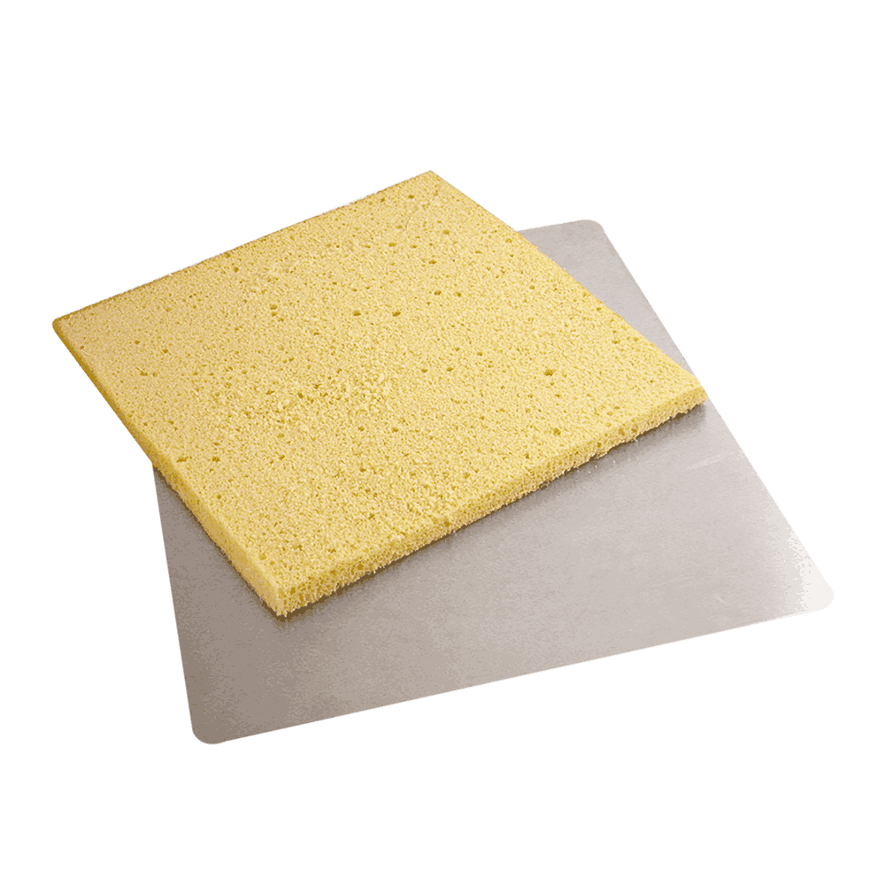 Ein rechteckiger, luftiger Tortenboden liegt auf einer flachen, silbernen Tortenunterlage mit abgerundeten Ecken.