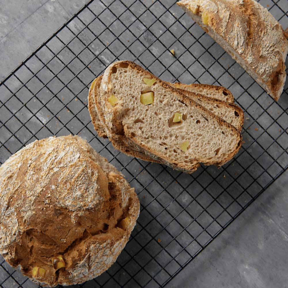Kartoffelbrot aus Kartoffelbrotmehl Frisch gebackenes, aufgeschnittenes Kartoffelbrot auf einem Trüffelgitter auf einer Küchenarbeitsplatte.