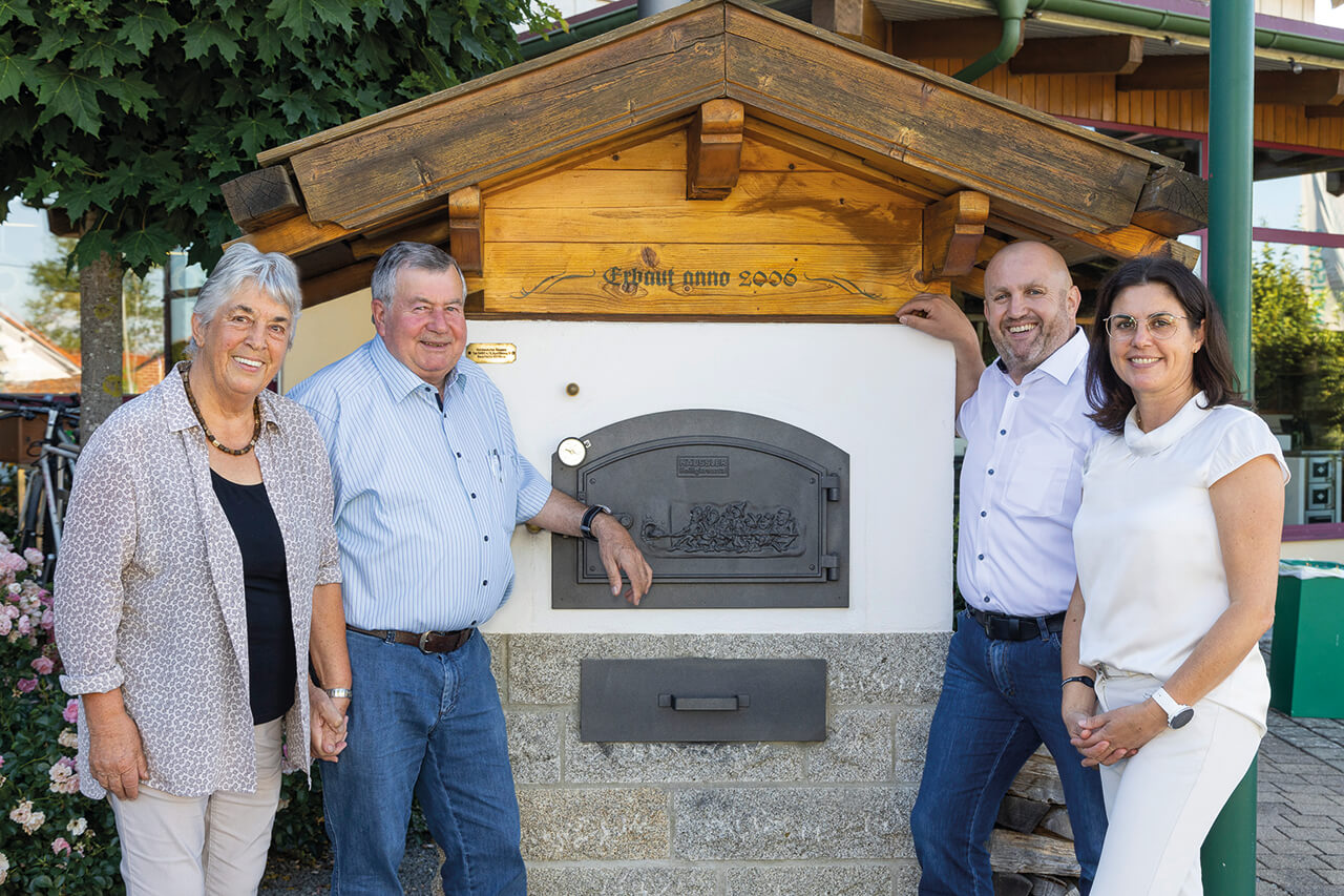 Familie_Häussler Familie Häussler steht vor einem traditionellen Holzbackofen.