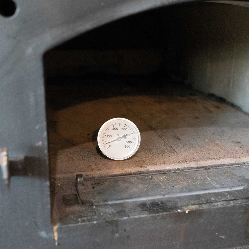 Thermometer zum Aufstellen Leerer Holzbackofen. Darin steht ein Thermometer