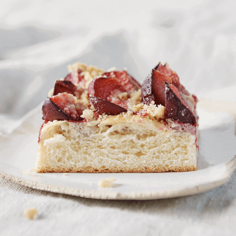 Rezept für Zwetschgendatschi saftiger Hefekuchen mit Zwetschgen und Streuseln auf einem weißen Teller