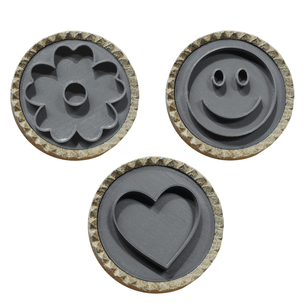 3 nebeneinanderliegende Brotstempel mit verschiedenen Motiven. Blume, Herz und Smiley