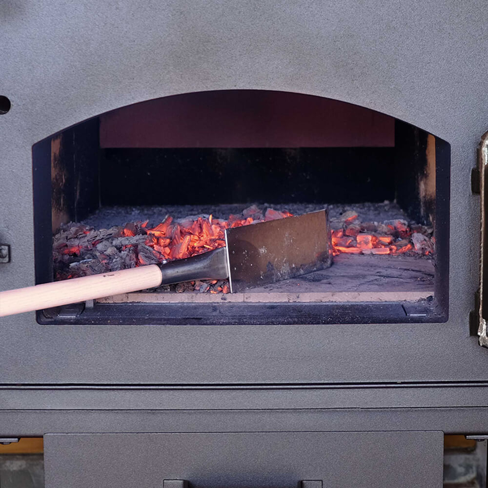 Holzbackofen mit Glutschieber: Die Glut wird von der rechten auf die linke Seite geschoben.