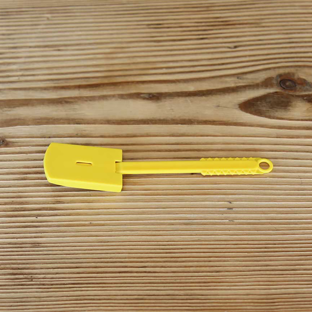 kleines gelbes Plastikmesser mit einer Rasierklinge und einer Schutzhülle auf einem Holzbrett liegend