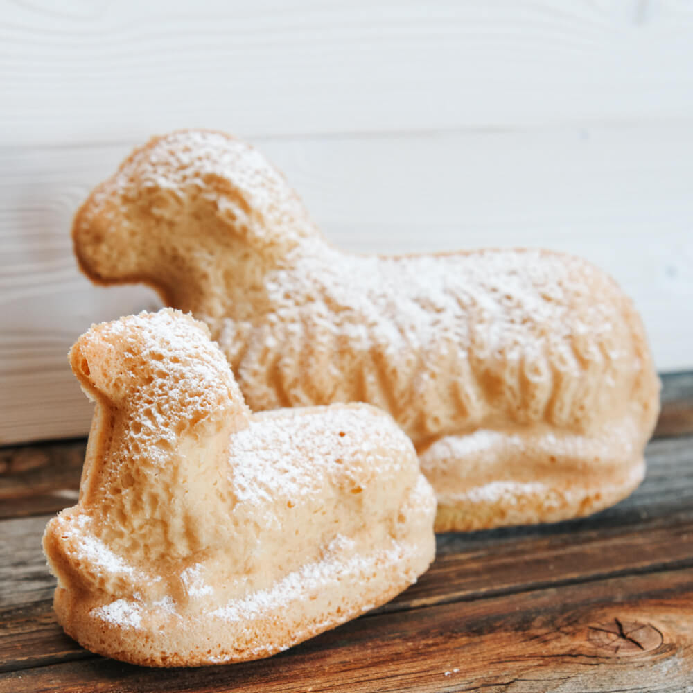 Rezept für Osterlamm Ein großes und ein kleines gebackenes Osterlamm, bestreut mit Puderzucker