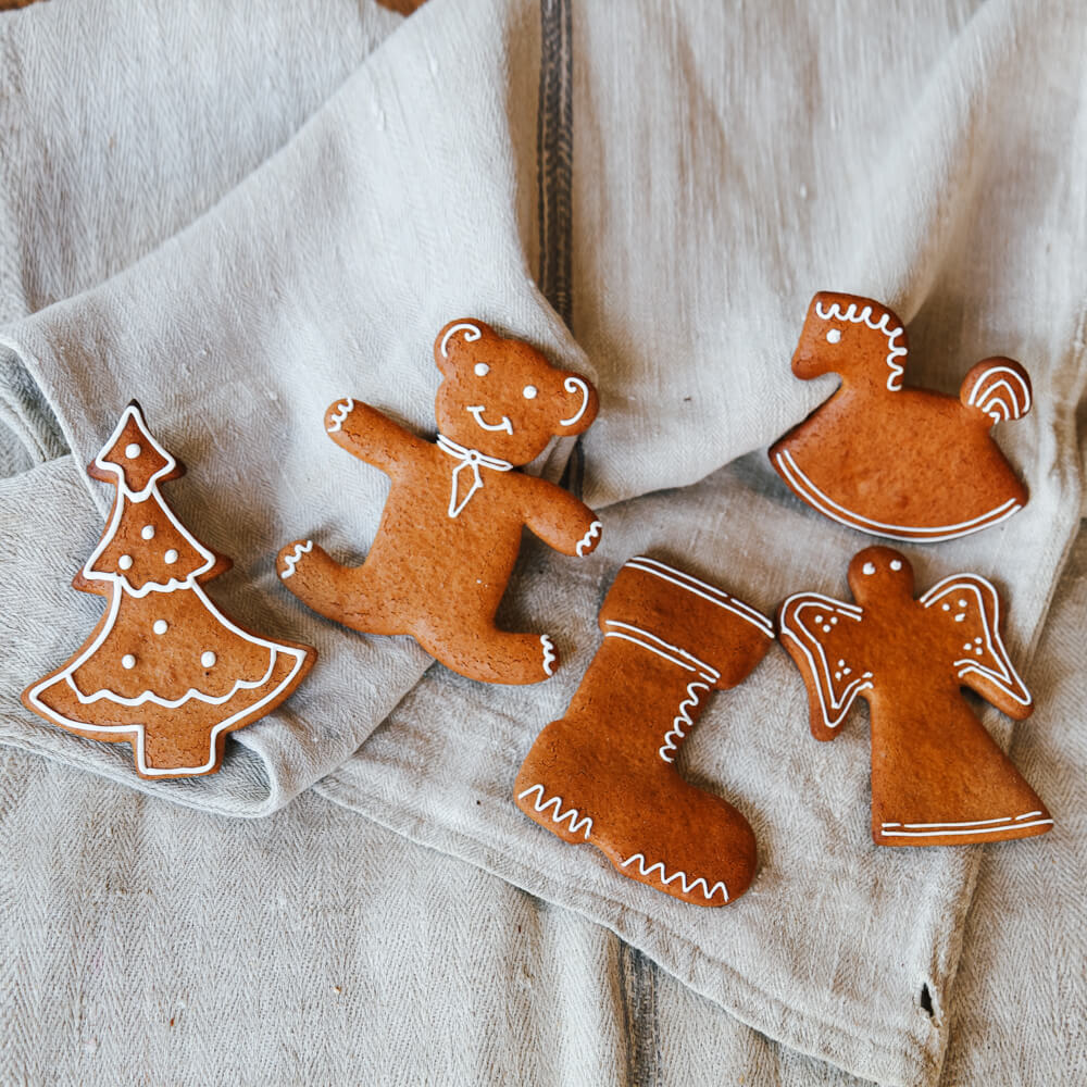 Rezept für Adelindes Dinkel-Honig-Lebkuchen Lebkuchen in verschiedene Formen zum Beispiel Schaukelpferd, Tannenbaum usw. mit Zuckerguss verziert auf einem hellgrauen Tuch