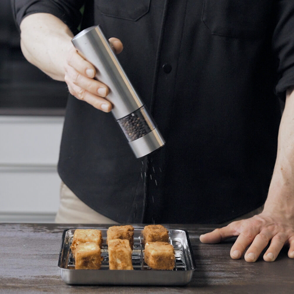 Der panierte Feta wird gewürzt.