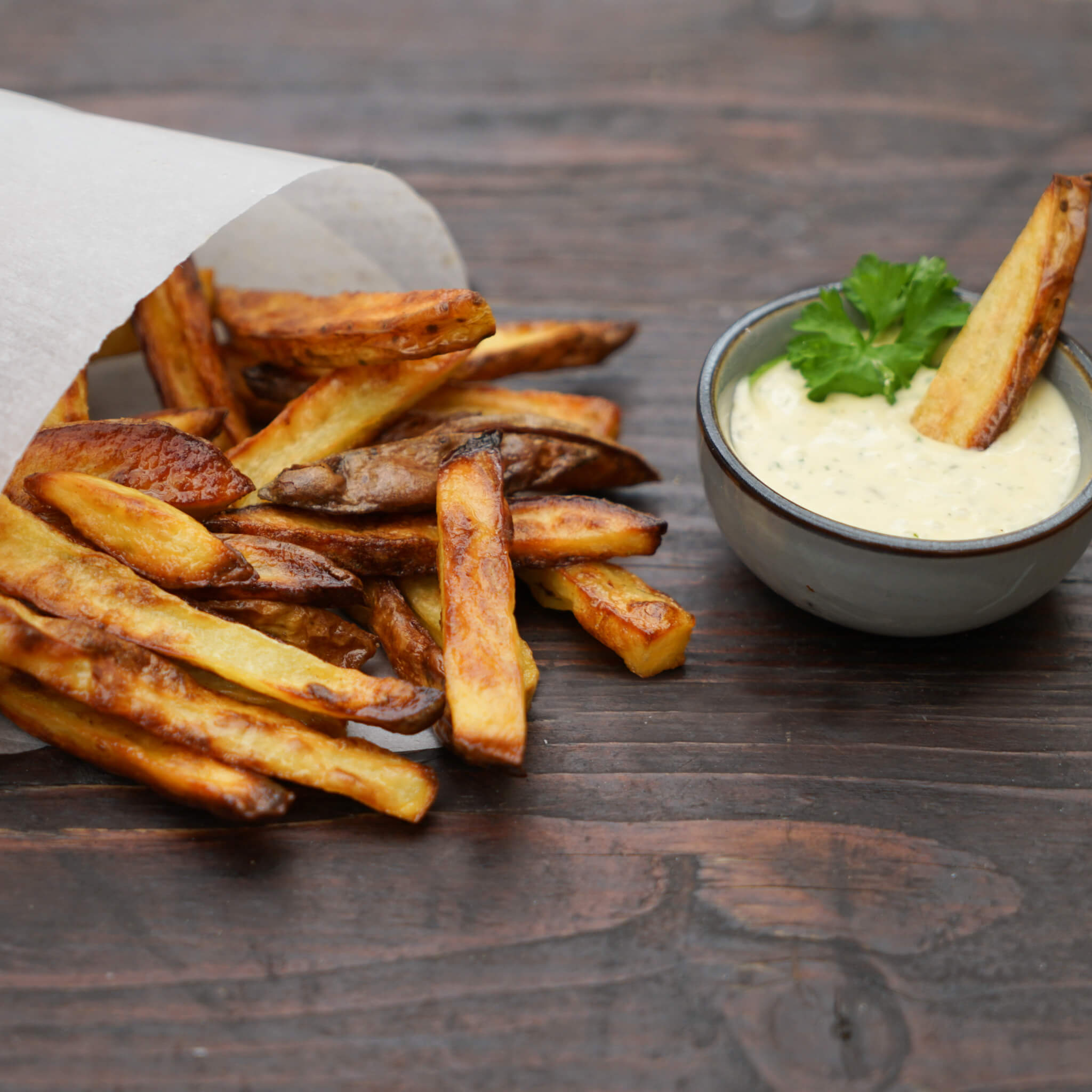 knusproge Pommes, eingeschlagen in einem Papier mit einer Schüssel Mayonaise 