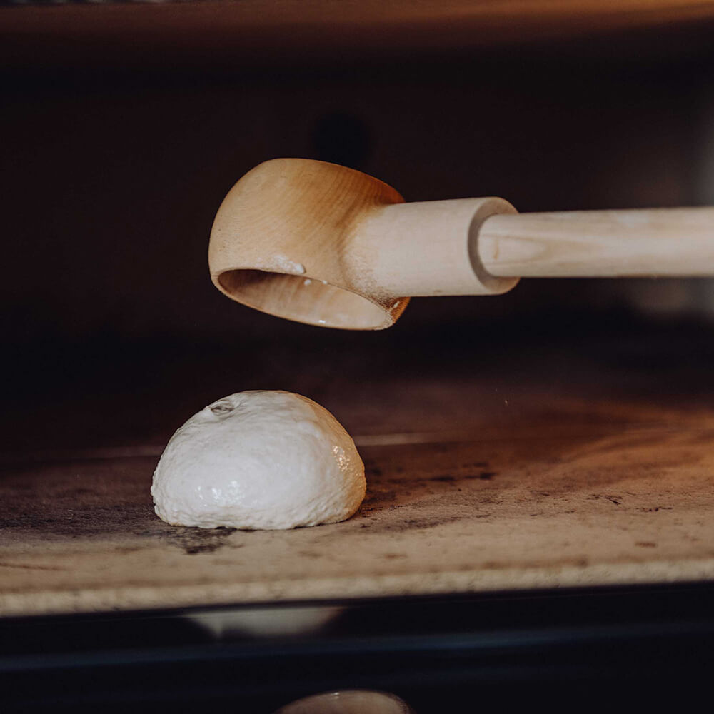 Ein Teigling wurde gerade mit einem Knauzenschießer in einen Elektrosteinbackofen eingeschossen und liegt nun auf dem Stein