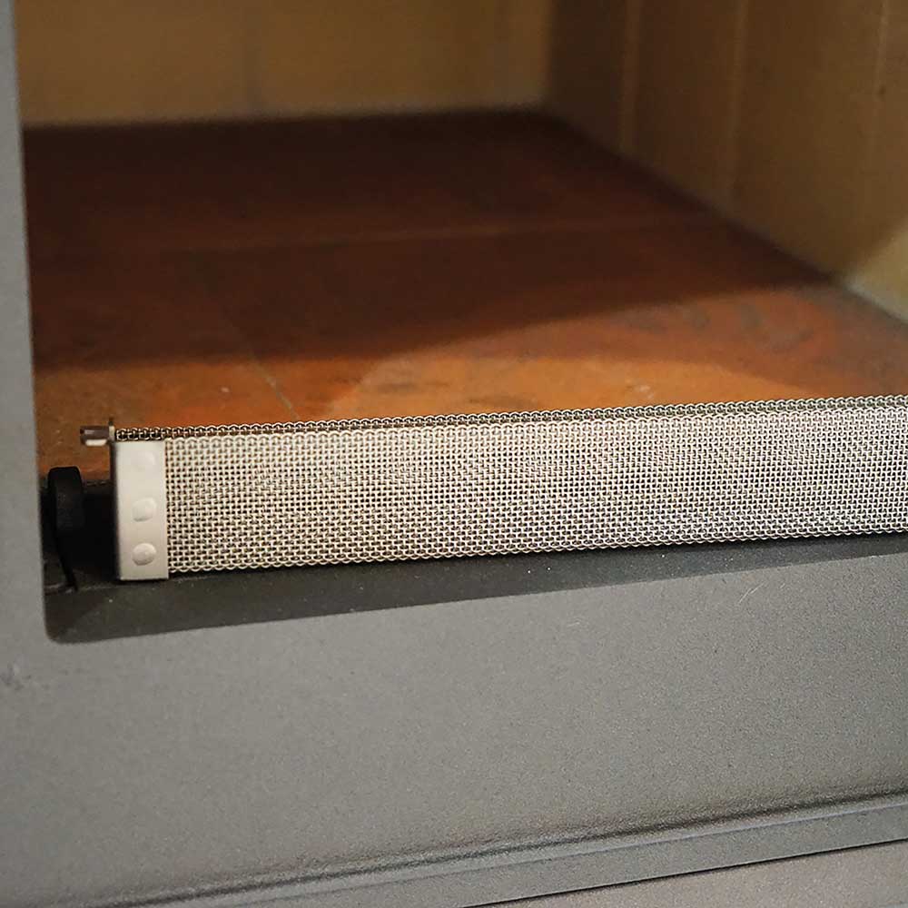 Smoker Einsatz, der gerade im Holzbakofen eingesetzt wird. Im Hintergrund sieht man die orange-farbenen Schamott-Steine