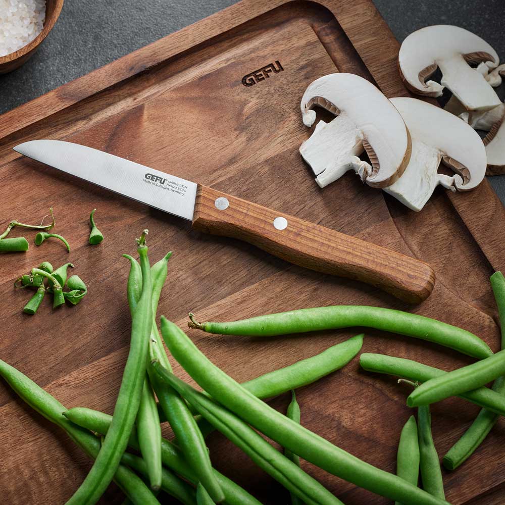 Gemüsemesser Gemüsemesser mit Walnussgriff auf einem Holzbrett mit Bohnen und Pilzen.