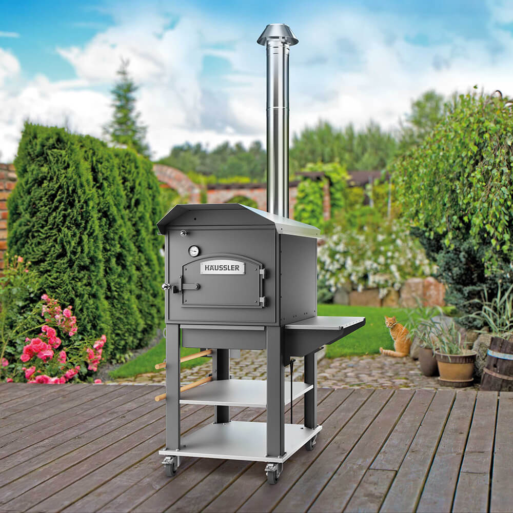 Gartenszene auf Holz-Terrasse. Darauf ist ein HABOGusto in Edelstahl-Ausführung zu sehen