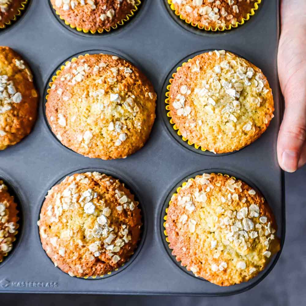 Muffinform mit 12 Mulden frische Muffins in Muffinbackform. Blech wird vom Bäcker gehalten