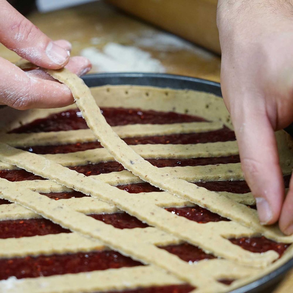 Backmischung Linzertorte Linzertorte in Herstellung. Zwei Hände, die die Teigstreifen auf die Torte legen.