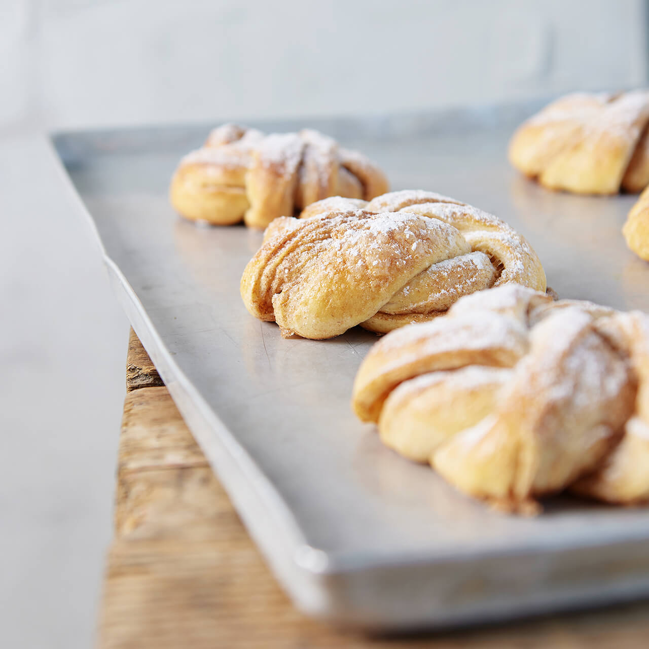 Zimtknoten_auf_Backblech Zimtknoten mit Puderzucker bestreut, frisch gebacken und auf einem Backblech liegend.