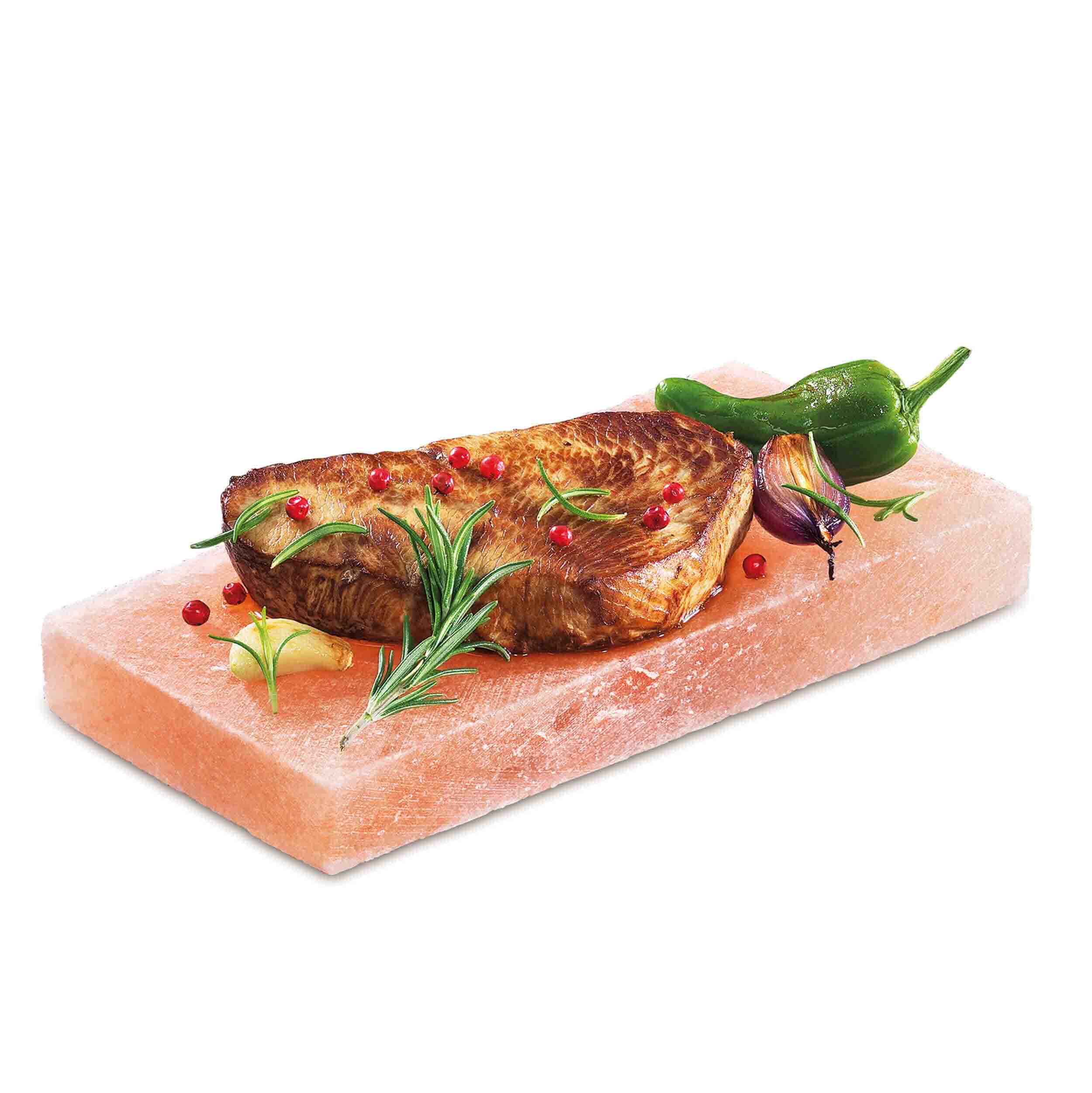 Salzplatte Rechteckige Salzplatte in rosa-orange Farbtönen, geeignet zum Grillen, Braten oder Servieren. Darauf liegt ein gebratenes Stak welches mit Rosmarinzweigen, Knoblauch, roten Beeren. einer grünen Chilli und einer roten Zwiebel garniert ist.