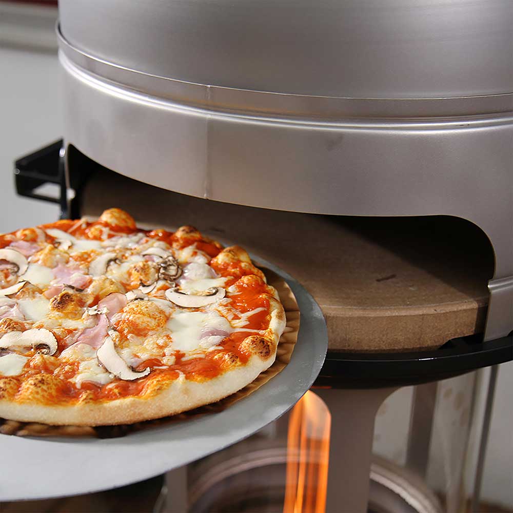 Pizzasteon wird mit einer Pizza befüllt, die auf einem Pizzaschieber liegt