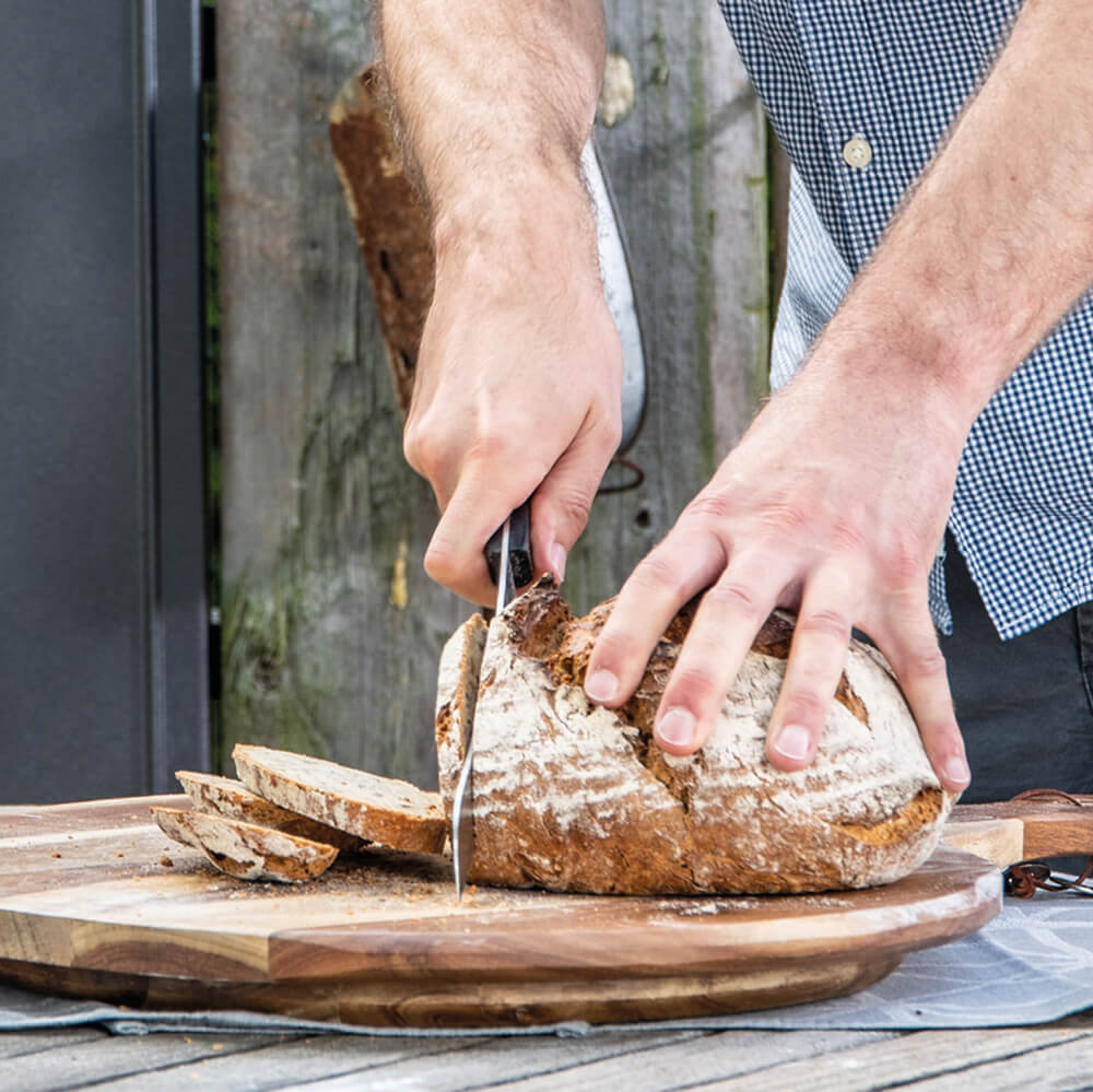 Brotmesser mit langer Wellenschliffklinge Knuspriges Brot, das mit einem Messer mit lange Klinge aufgeschnitten wird