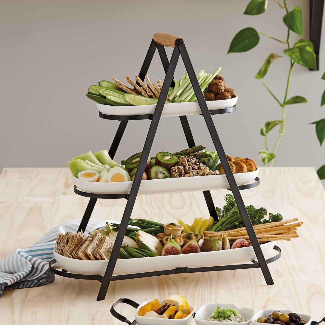 Aufgestellter 3-etagiger Servierturm auf einem Tisch, gefüllt mit verschiedenen Snacks.