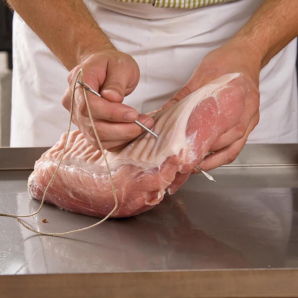 Dressiernadel sticht durch ein Stück Fleisch