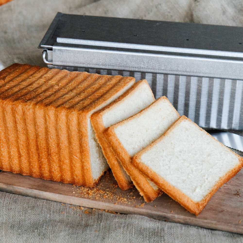 selbstgemachtes aufgeschnittenes Toastbrot. Im HIntergrund ist die Toastbrotform zu sehen