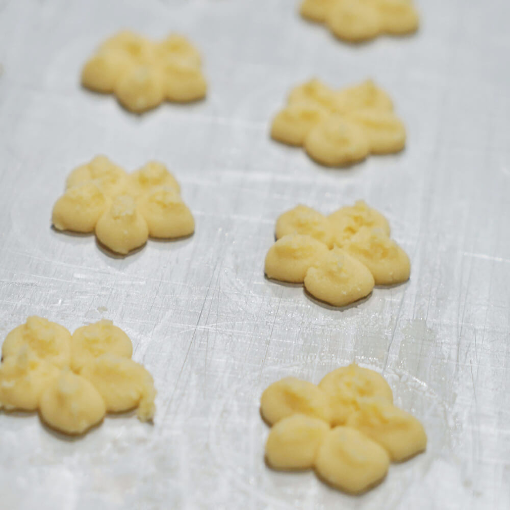 Gebäckpresse Runde Plätzchen in Blumenform auf einem grauen Blech.