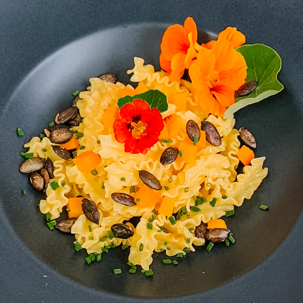 frsiche Kürbisnudeln in Butter geschwenkt Kürbisnudeln mit Kürbiskerne auf einem schwarzen Nudelteller