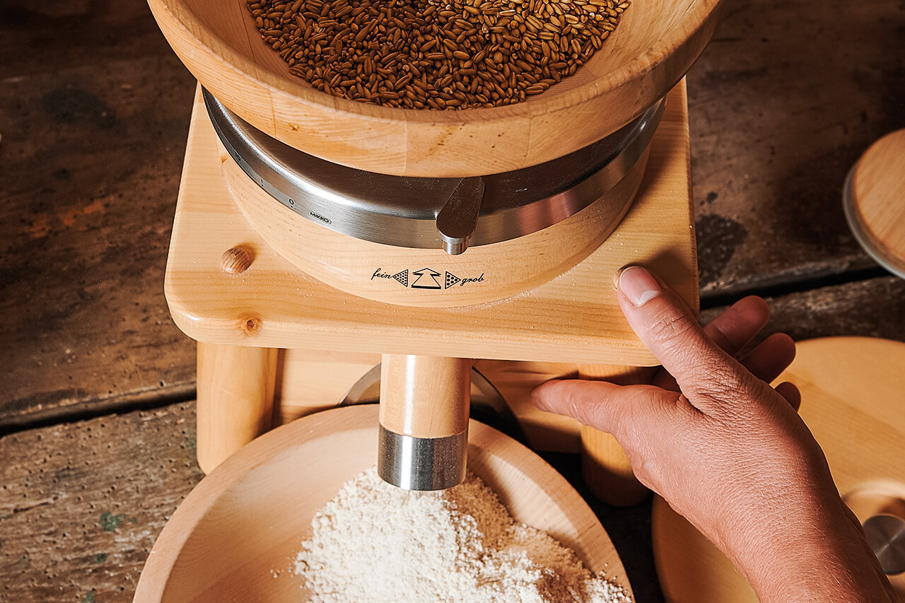 Getreidemühle in Betrieb Getreidemühle in Betrieb - feines Mehl rieselt aus dem Auslass, während das Mahlwerk arbeitet.