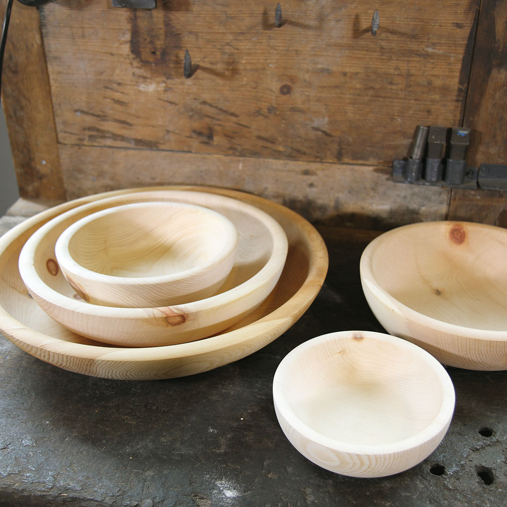 Verschiedene große Holzschüsseln aus Zirbelkiefer auf einer Arbeitsfläche 