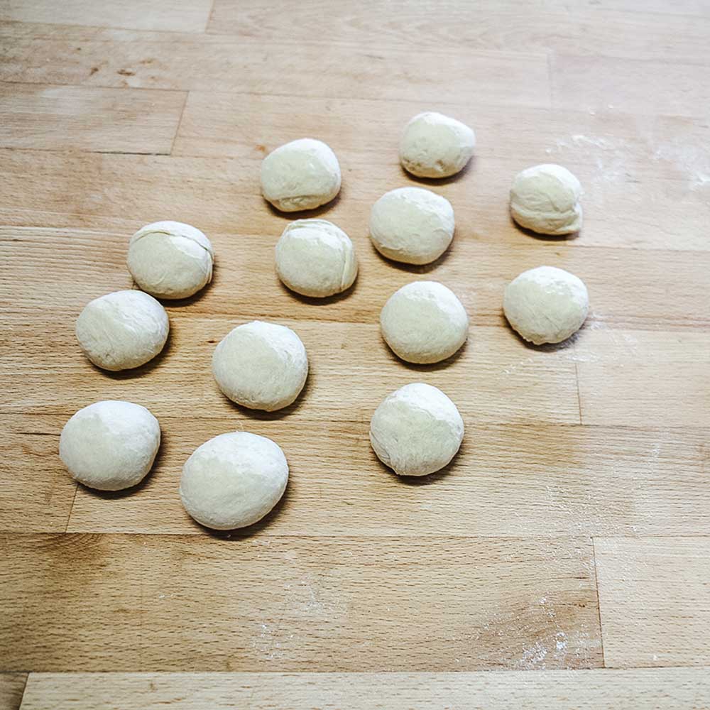 Rund geformte Teiglinge, die mit dem Teigteiler abgestochen wurden, auf einer Arbeitsplatte.