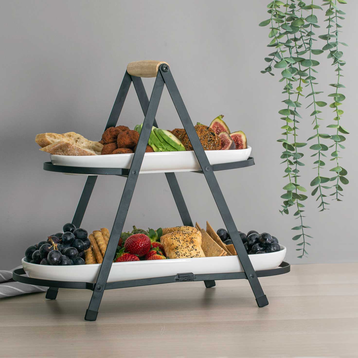 Servierturm 2-etagig Aufgestellter 2-etagiger Servierturm auf einem Tisch, gefüllt mit verschiedenen Snacks.