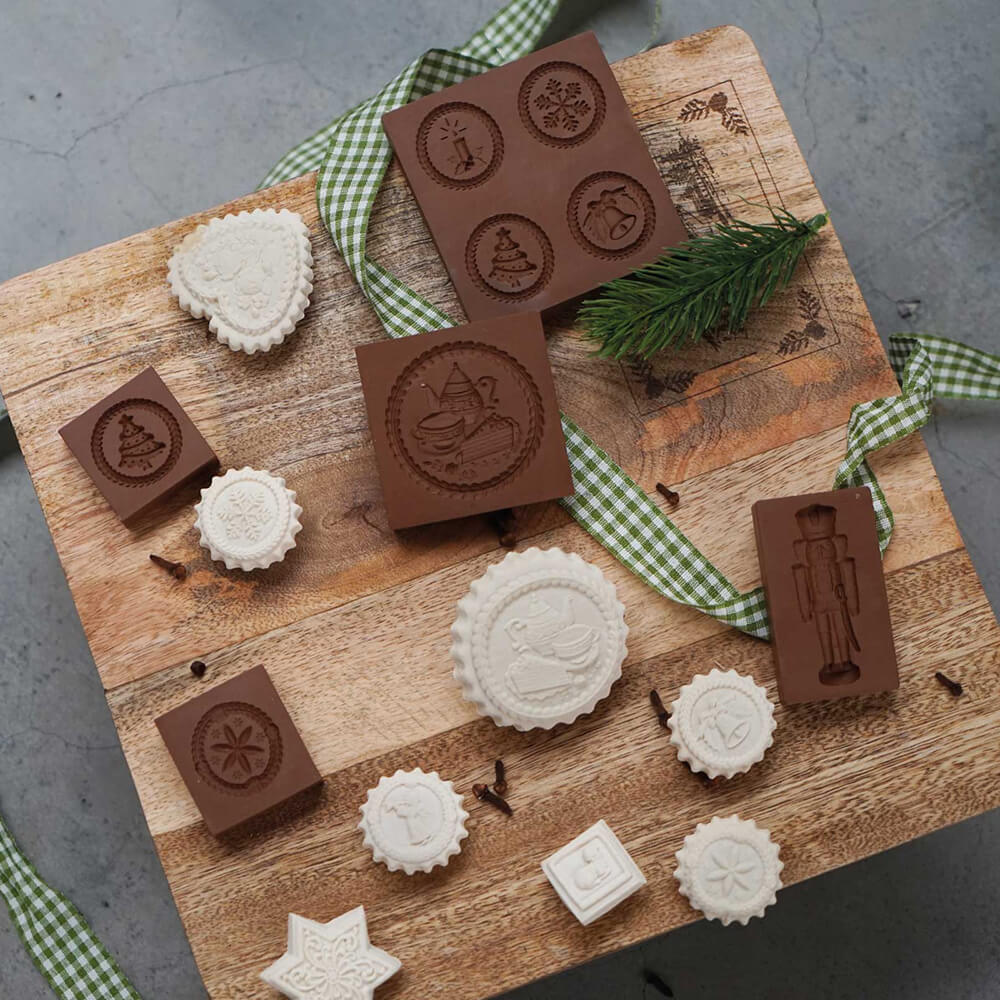 Verschiedene Springerle-Model Formen sowie fertiggebackene Springerle. Diese liegen auf einer Holzoberfläche.