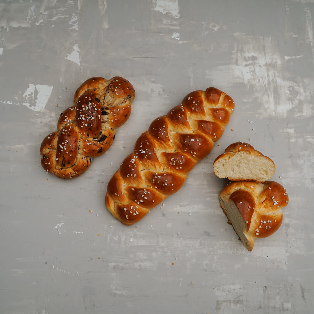 Rezept für Brioche Hefezöpfe gebackene Brioche Zöpfe mit Hagelzucker bestreut auf einem grauen Hintergrund
