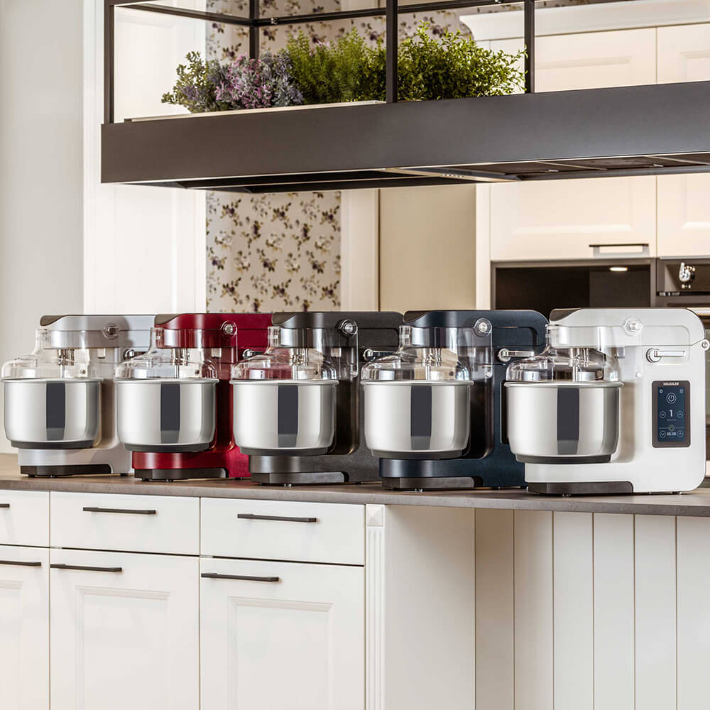 NOVA Teigknetmaschine NOVA Teigknetmaschinen in verschiedenen Farben nebeneinander in einer Küche.