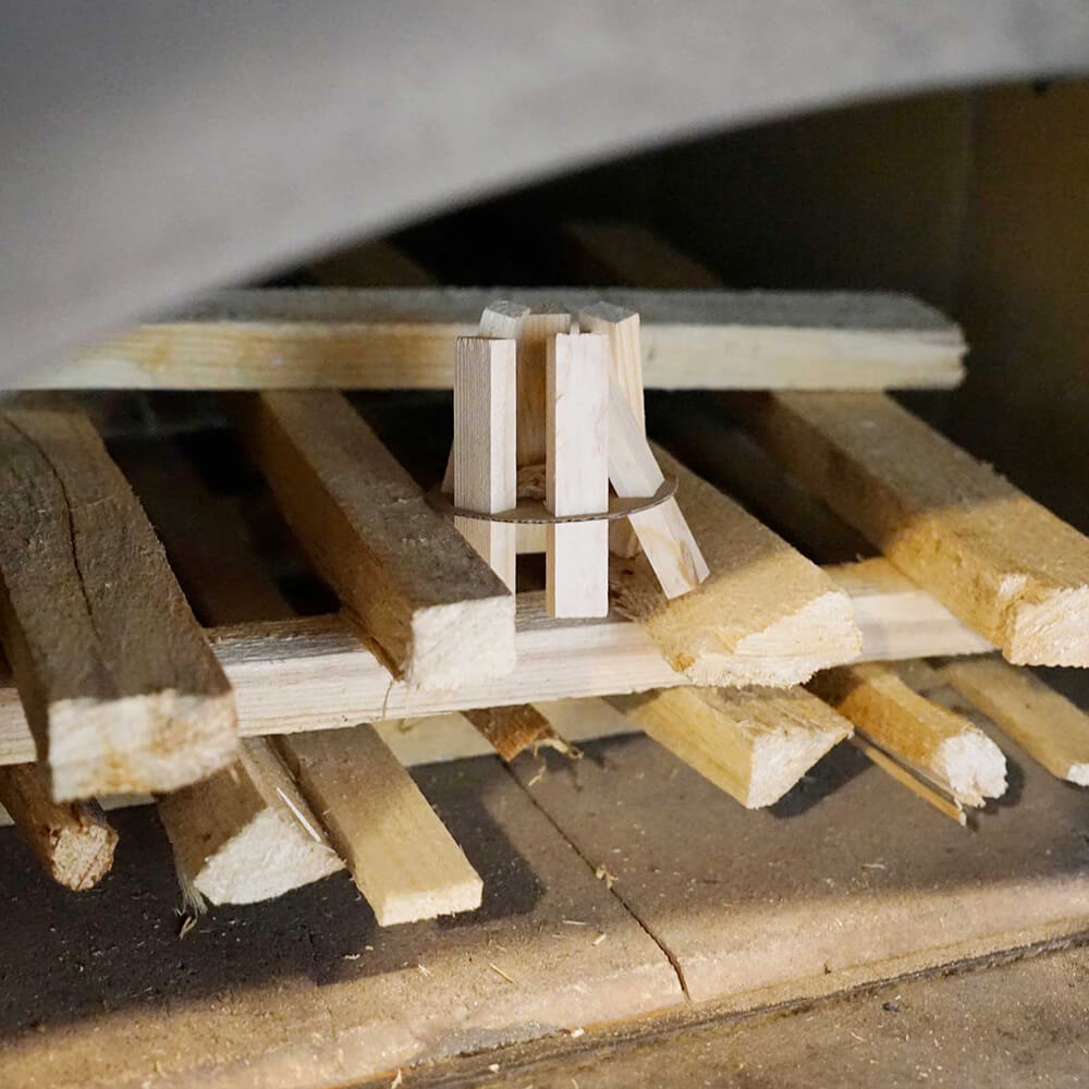 Gestapeltes Holz im Holzbackofen. Darauf ist ein Teil des Feuerkit's zu sehen.