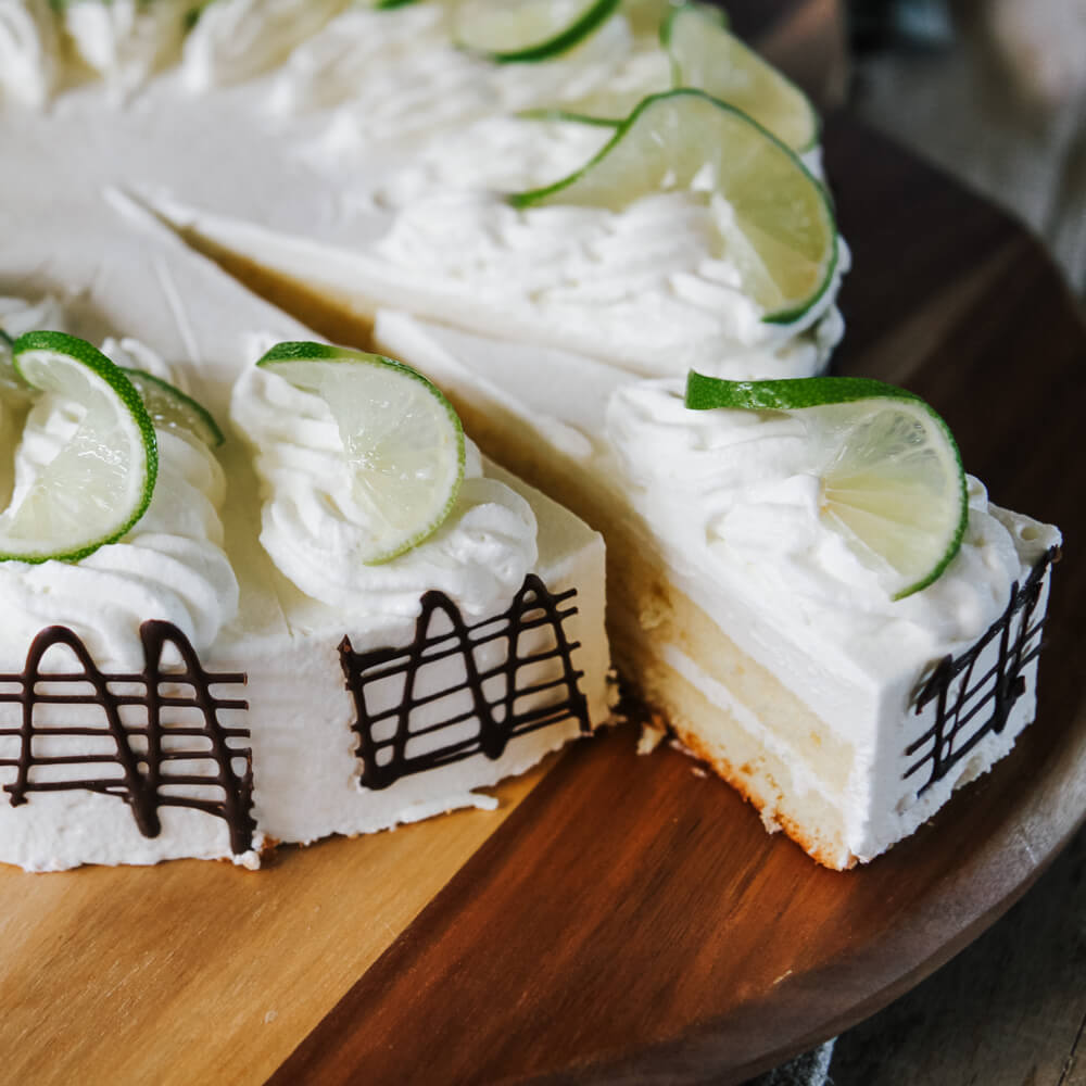 erfrischende Limetten-Joghurt-Sahnetorte garniert mit Schokolade, Sahne und frischen Limettenscheiben