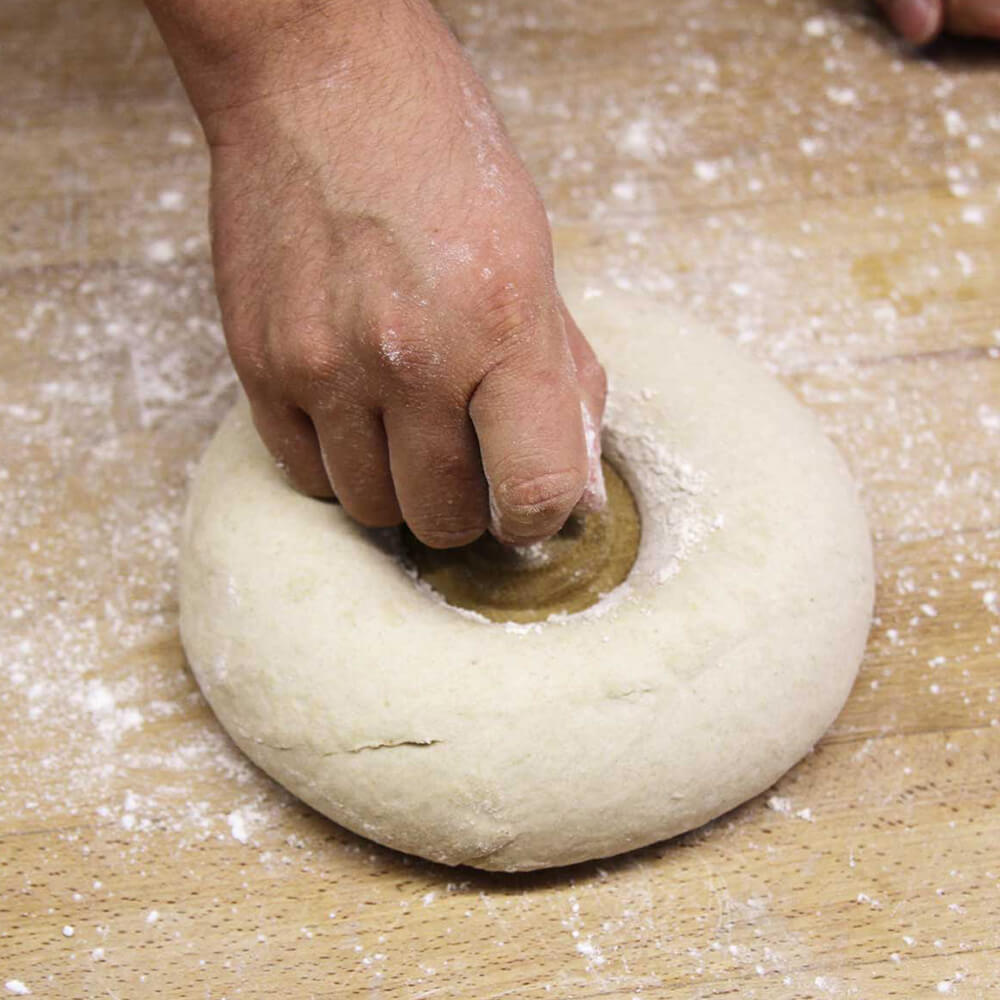 Brotstempel rund geformter Brotteig, in die Mitte wird der Stempel fest eingedrückt