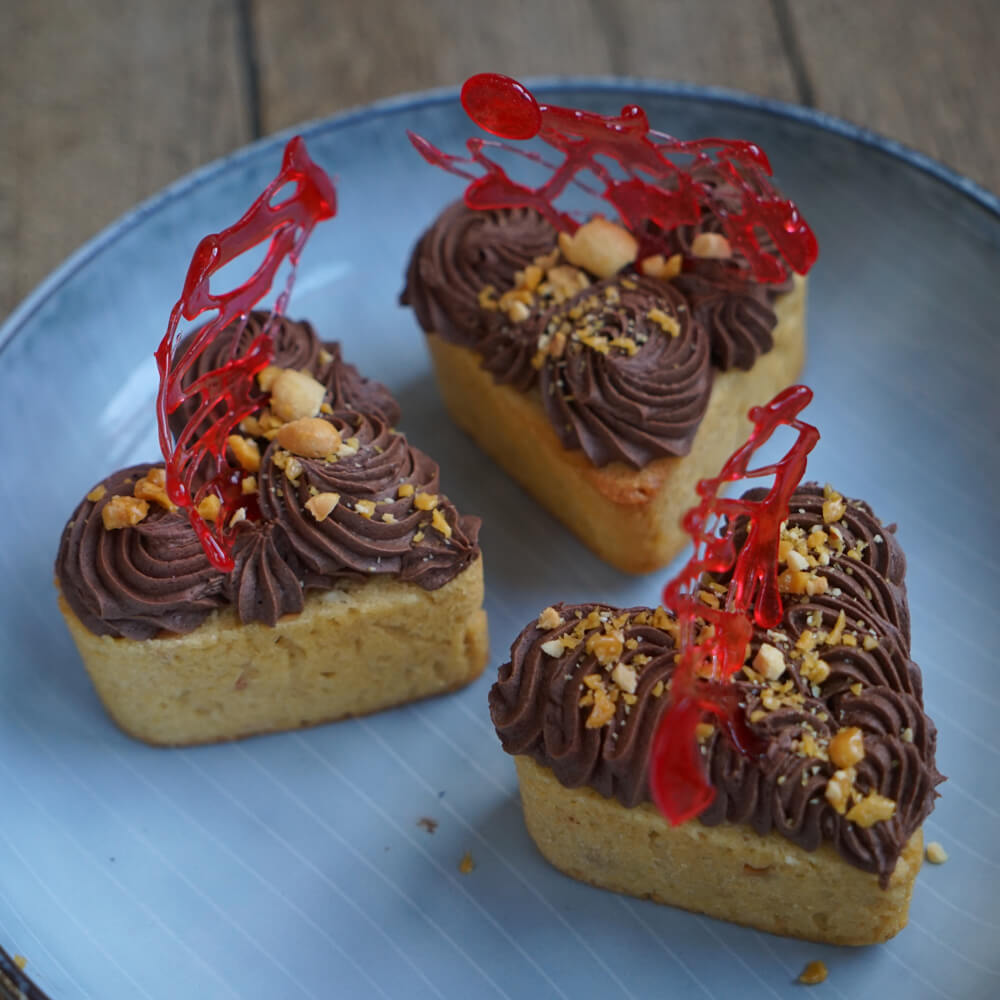 Erdnuss Cupcakes mit Schoko-Topping und Erdnusskrokant auf einem blauen Teller serviert