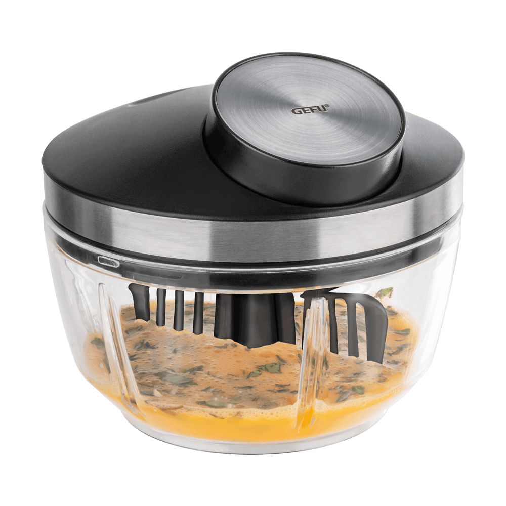 Durchsichtige Plastikschüssel mit einem Plastikdeckel und Seilzugzugmechanismus, am Deckel ist ein Rühr-Einsatz befestigt und in der Schüssel befinden sich verquirlte Eier mit Schnittlauch